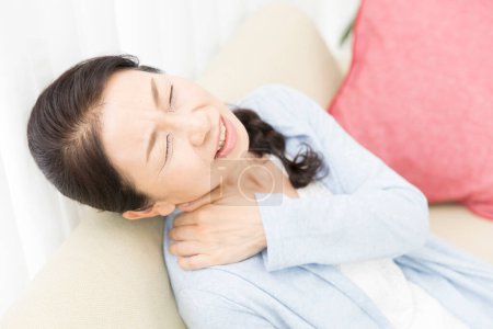 Foto de Mujer con dolor de cuello en sofá - Imagen libre de derechos