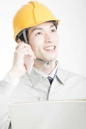 Téléchargez les photos : Portrait de beau jeune homme japonais en casque de sécurité posant sur fond de studio blanc - en image libre de droit