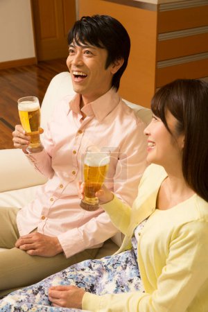 Téléchargez les photos : Jeune couple asiatique boire de la bière à la maison au salon - en image libre de droit