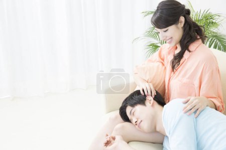 Téléchargez les photos : Asiatique couple détente sur canapé à la maison - en image libre de droit