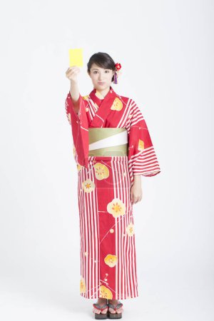 Foto de Mujer usando japonés kimono celebración amarillo tarjeta en blanco - Imagen libre de derechos