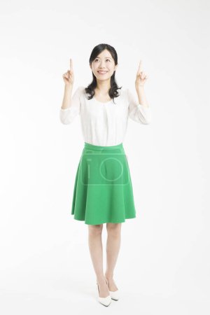 Téléchargez les photos : Belle femme d'affaires japonaise pointant vers le haut avec les doigts sur fond blanc - en image libre de droit