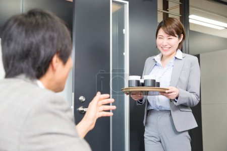 Photo for Asisn businesswoman brings  coffee to meeting room - Royalty Free Image