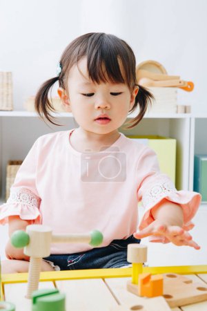 Photo for Closeup shot of cute Japanese girl playing with toys at home interior - Royalty Free Image