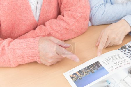Téléchargez les photos : Couple aîné avec magazine à table - en image libre de droit