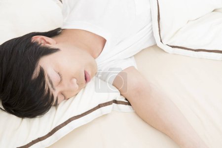 Photo for Asian man sleeping on bed in bedroom - Royalty Free Image