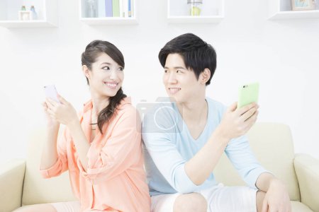 Photo for Couple with smart phones in living room - Royalty Free Image
