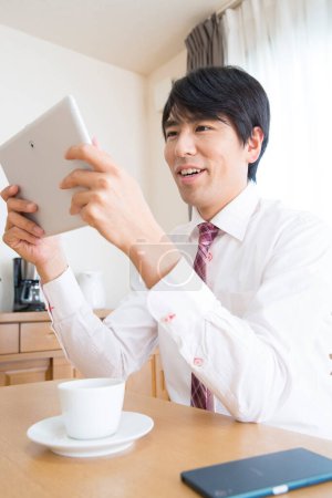 Téléchargez les photos : Jeune homme d'affaires utilisant une tablette le matin - en image libre de droit