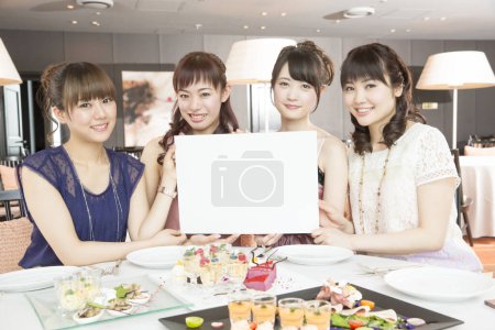 three young asian women with blank card  in restaurant