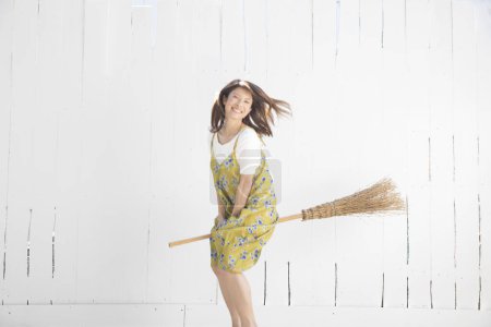 Photo for Happy asian young woman flying on broom - Royalty Free Image