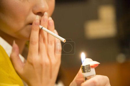 Téléchargez les photos : Gros plan asiatique femme fumer cigarette dans café - en image libre de droit