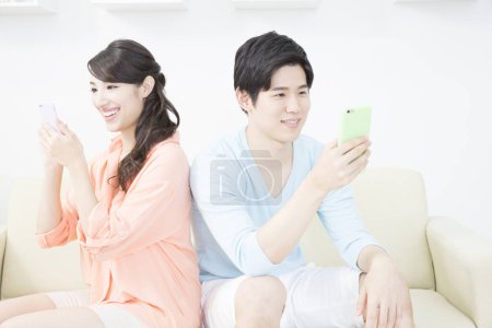 Photo for Couple using smart phones on sofa - Royalty Free Image