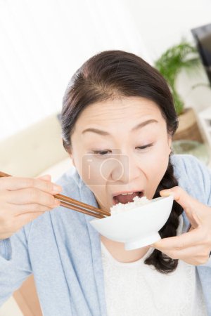 Téléchargez les photos : Asiatique femme manger riz avec baguettes - en image libre de droit