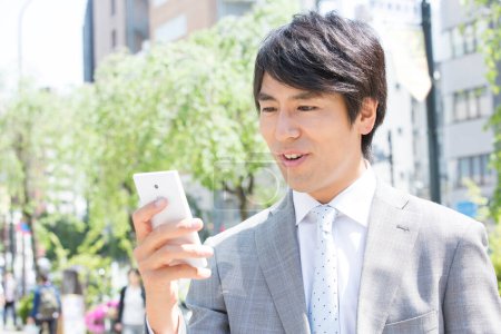 Téléchargez les photos : Jeune homme d'affaires avec téléphone portable dans la ville - en image libre de droit