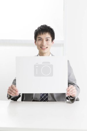 Photo for Close-up portrait of young japanese businessman showing plank placard - Royalty Free Image