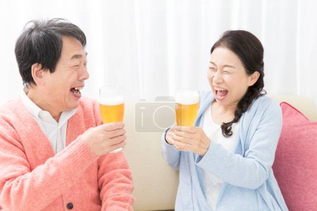 Téléchargez les photos : Couple aîné avec bière à la maison - en image libre de droit