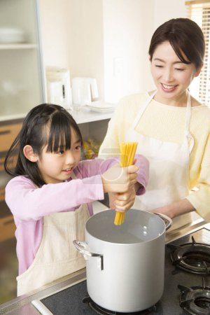Foto de Asian mother with daughter cooking pasta - Imagen libre de derechos