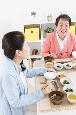 Foto de Senior asiático pareja teniendo comida en cocina - Imagen libre de derechos