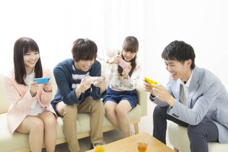 Téléchargez les photos : Jeunes amis asiatiques utilisant des téléphones intelligents - en image libre de droit
