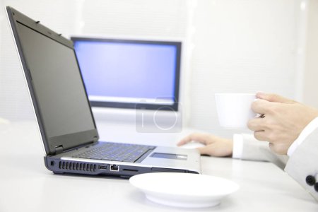 Téléchargez les photos : Homme avec tasse de café et ordinateur portable au bureau - en image libre de droit