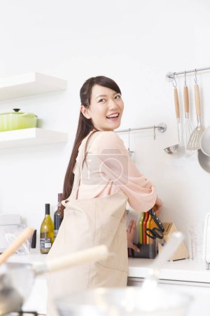 Foto de Hermosa mujer japonesa en delantal cocina en la cocina - Imagen libre de derechos