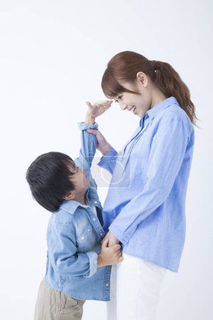 Téléchargez les photos : Portrait de jeune asiatique mère et son mignon fils posant en studio - en image libre de droit