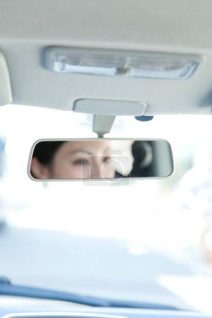 Téléchargez les photos : Femme dans la voiture réfléchissant dans le miroir - en image libre de droit
