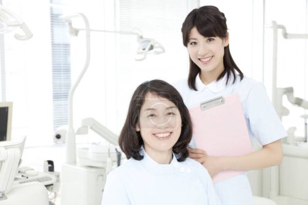 Téléchargez les photos : Infirmière souriante et patiente en clinique dentaire - en image libre de droit