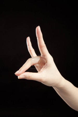 Téléchargez les photos : Gros plan de la main de la femme montrant un geste sur fond noir - en image libre de droit