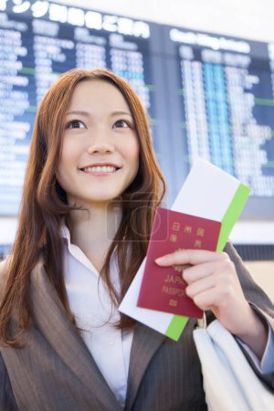 Téléchargez les photos : Femme d'affaires tenant un passeport avec billet et souriant - en image libre de droit