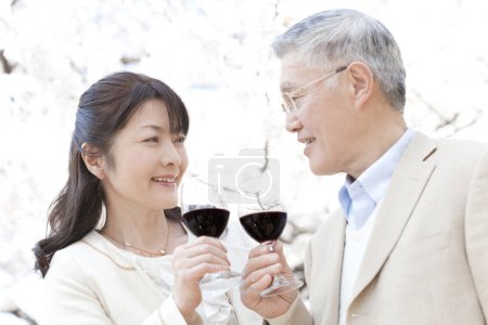 Téléchargez les photos : Portrait de couple asiatique senior buvant du vin dans le jardin - en image libre de droit