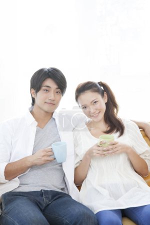 Téléchargez les photos : Couple relaxant sur canapé avec café - en image libre de droit