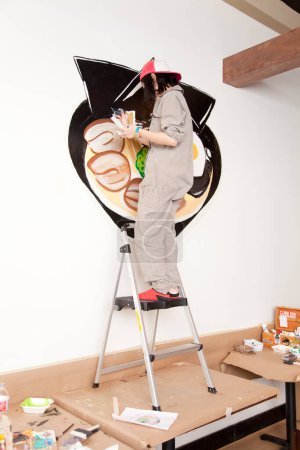 Foto de Joven trabajadora dedcorating pared en moderno restaurante - Imagen libre de derechos