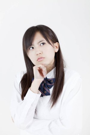 Téléchargez les photos : Portrait studio de fille japonaise réfléchie en uniforme scolaire - en image libre de droit
