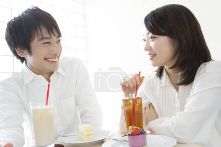 Téléchargez les photos : Un homme et une femme assis à une table avec des gâteaux et un verre - en image libre de droit
