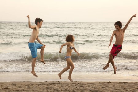 Téléchargez les photos : Jeunes asiatiques jouant sur une plage, concept vacances d'été - en image libre de droit