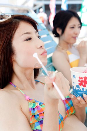 Téléchargez les photos : Asiatiques femmes manger de la glace sur la plage - en image libre de droit