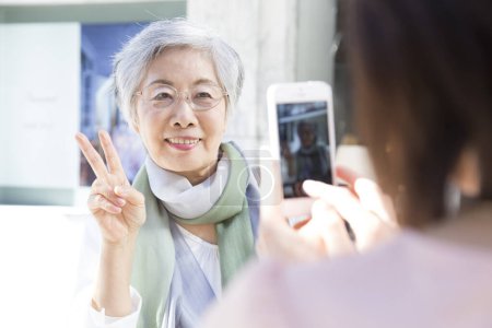 Foto de Mujer joven tomando fotos de mujer mayor con teléfono inteligente - Imagen libre de derechos