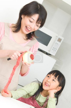 Foto de Sonriente japonesa mujer y su hija cocinar en cocina - Imagen libre de derechos