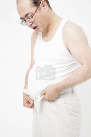 Photo for Fat asian man  putting on trousers - Royalty Free Image