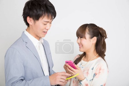Foto de Joven hombre y mujer con teléfonos inteligentes sobre fondo blanco - Imagen libre de derechos
