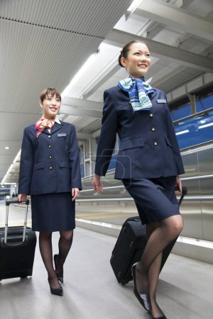 Photo for Two flight attendants walking in airport - Royalty Free Image