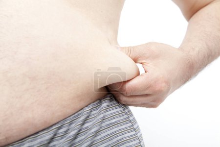 Téléchargez les photos : Gros homme en sous-vêtements montre des dépôts de graisse dans l'abdomen. Concept de mauvaise nutrition, mode de vie sédentaire - en image libre de droit