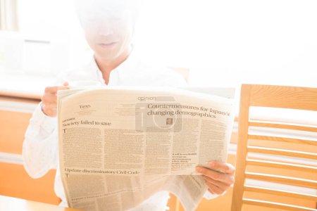 Photo for Young man reading newspaper at home - Royalty Free Image