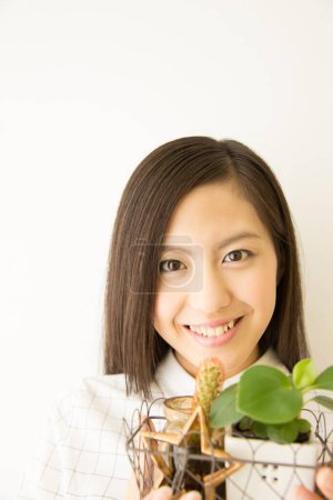 Foto de Sonriente asiático chica con plantas en casa - Imagen libre de derechos