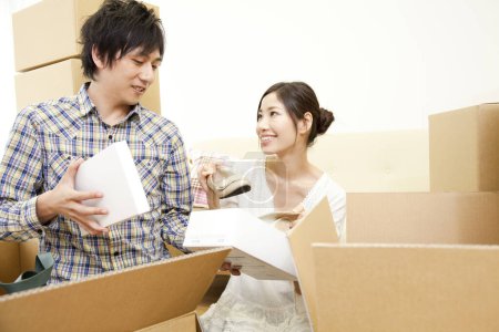 Photo for Asian couple with cardboard boxes moving in new house - Royalty Free Image
