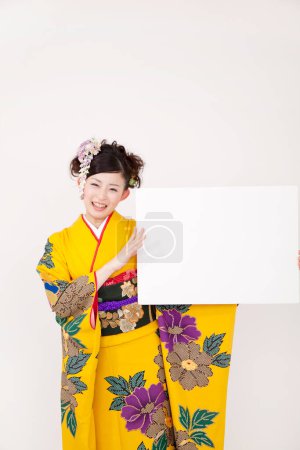 asiatique jeune femelle dans traditionnel kimono avec blanc carte sur fond blanc