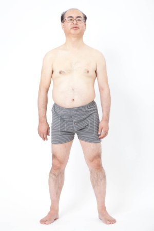 Téléchargez les photos : Japonais gros homme en sous-vêtements montre des dépôts de graisse dans l'abdomen. Concept de mauvaise nutrition, mode de vie sédentaire - en image libre de droit