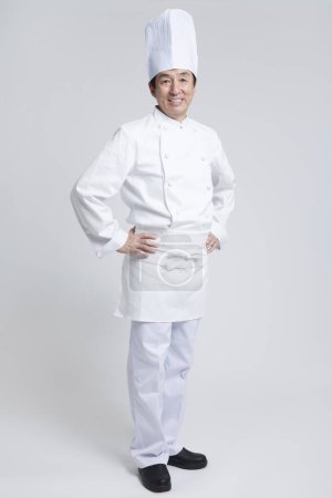 Téléchargez les photos : Jeune asiatique chef homme en uniforme blanc sur fond gris. - en image libre de droit