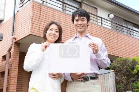 Foto de Asiático pareja con papel tarjeta en frente de nuevo casa - Imagen libre de derechos